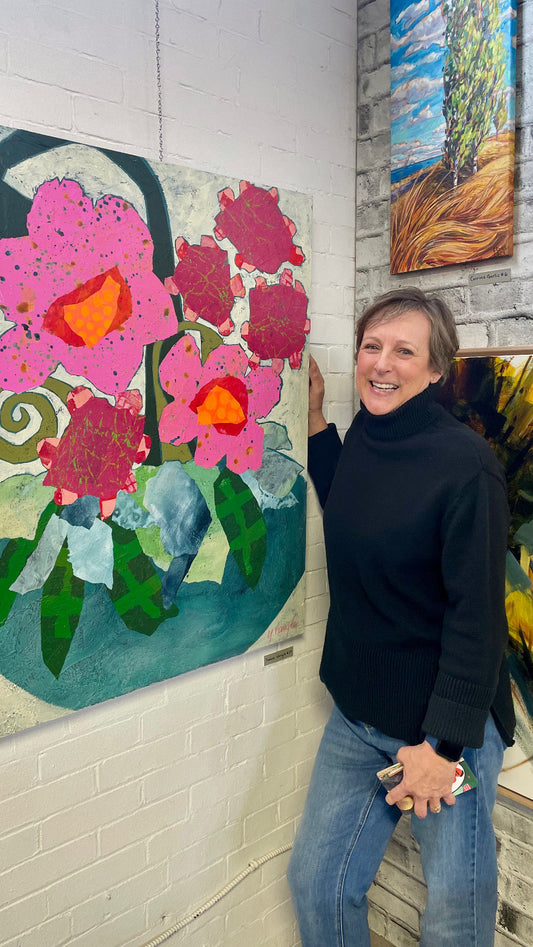 Canadian artist Yvonne Nangle standing beside colourful abstract floral painting