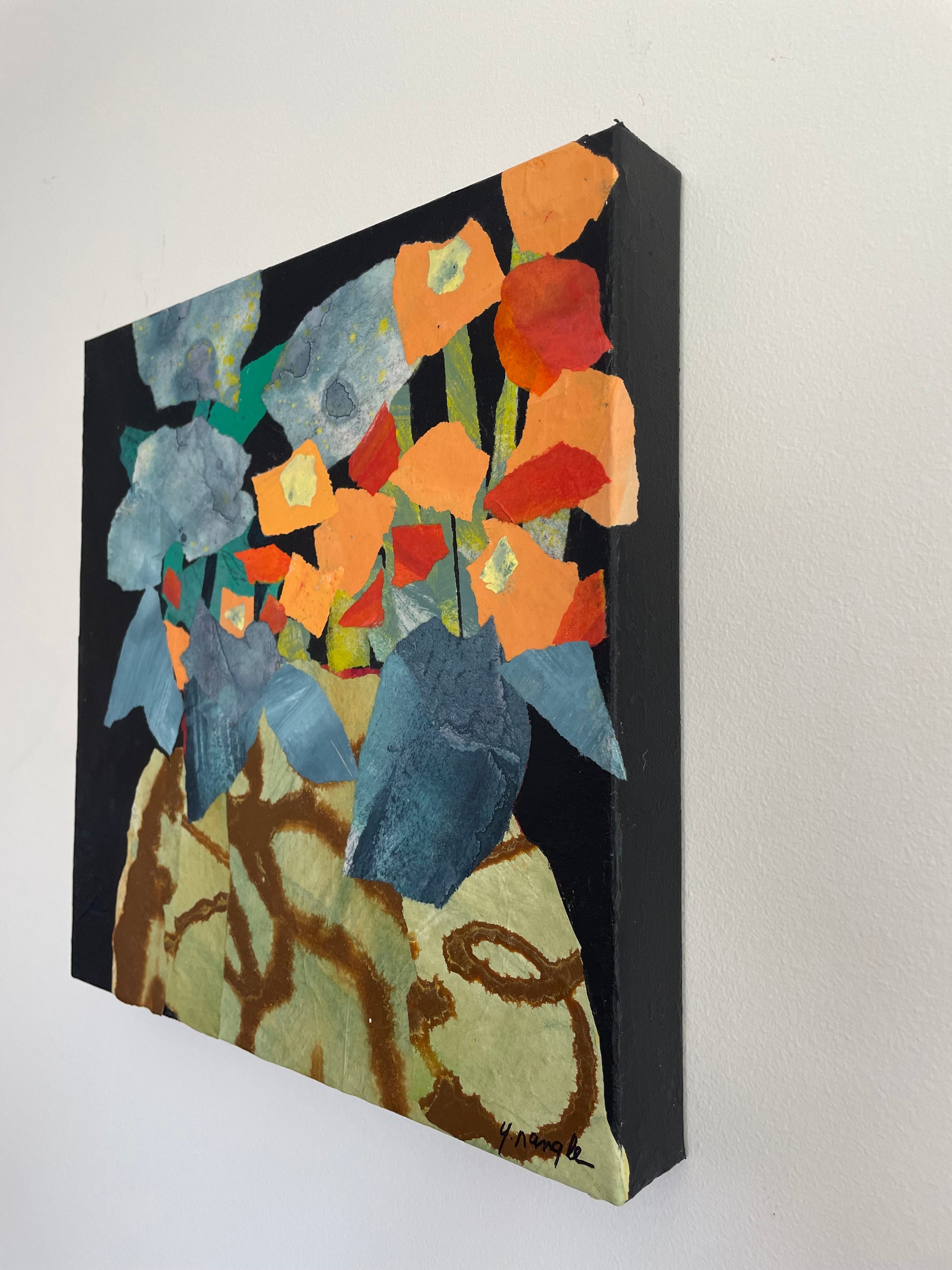 right side view of abstract floral painting showing layered painted paper texture with blue and red shapes on dark background