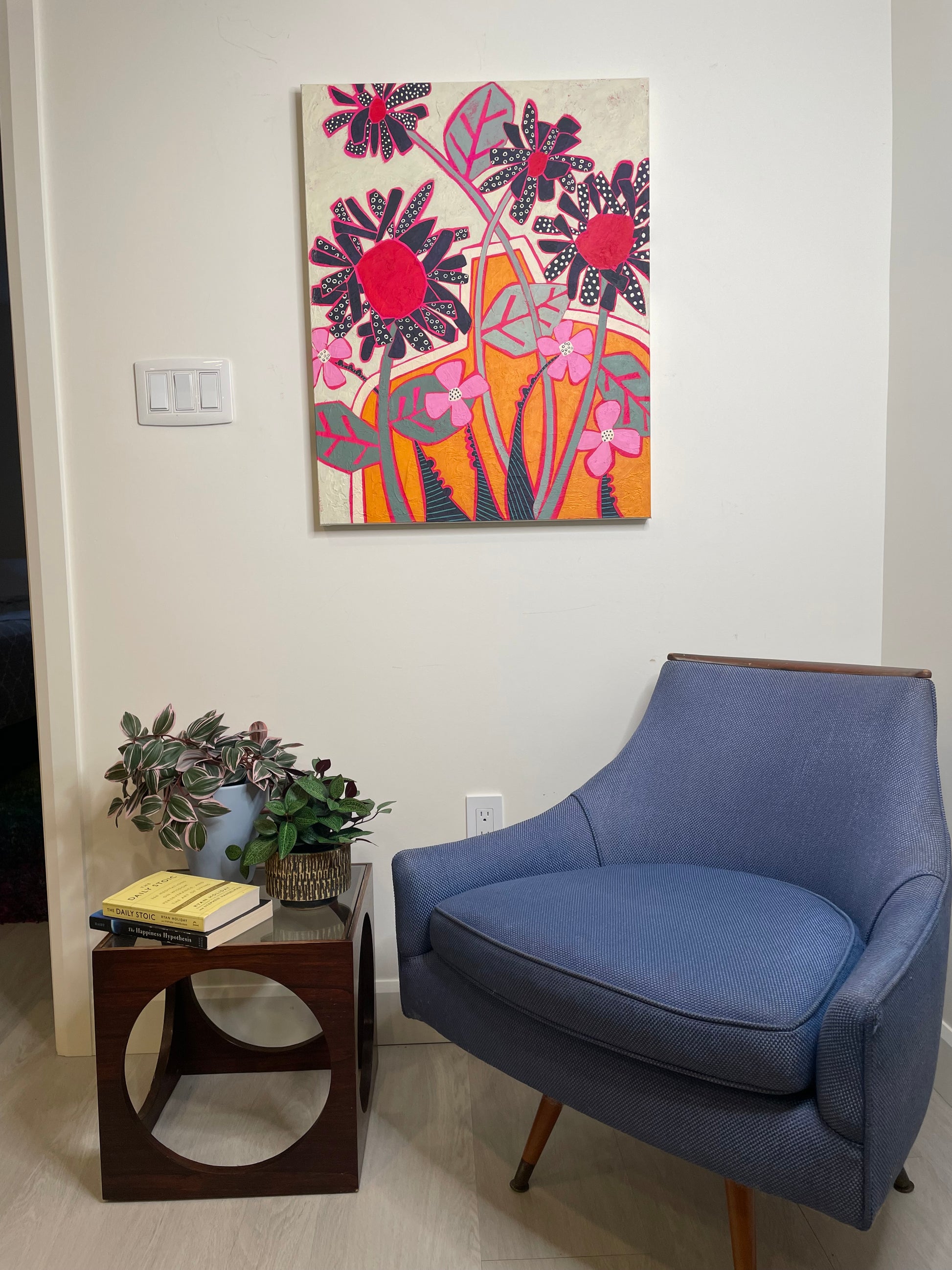 Abstract floral painting with black daisies and orange vase displayed in a modern living room