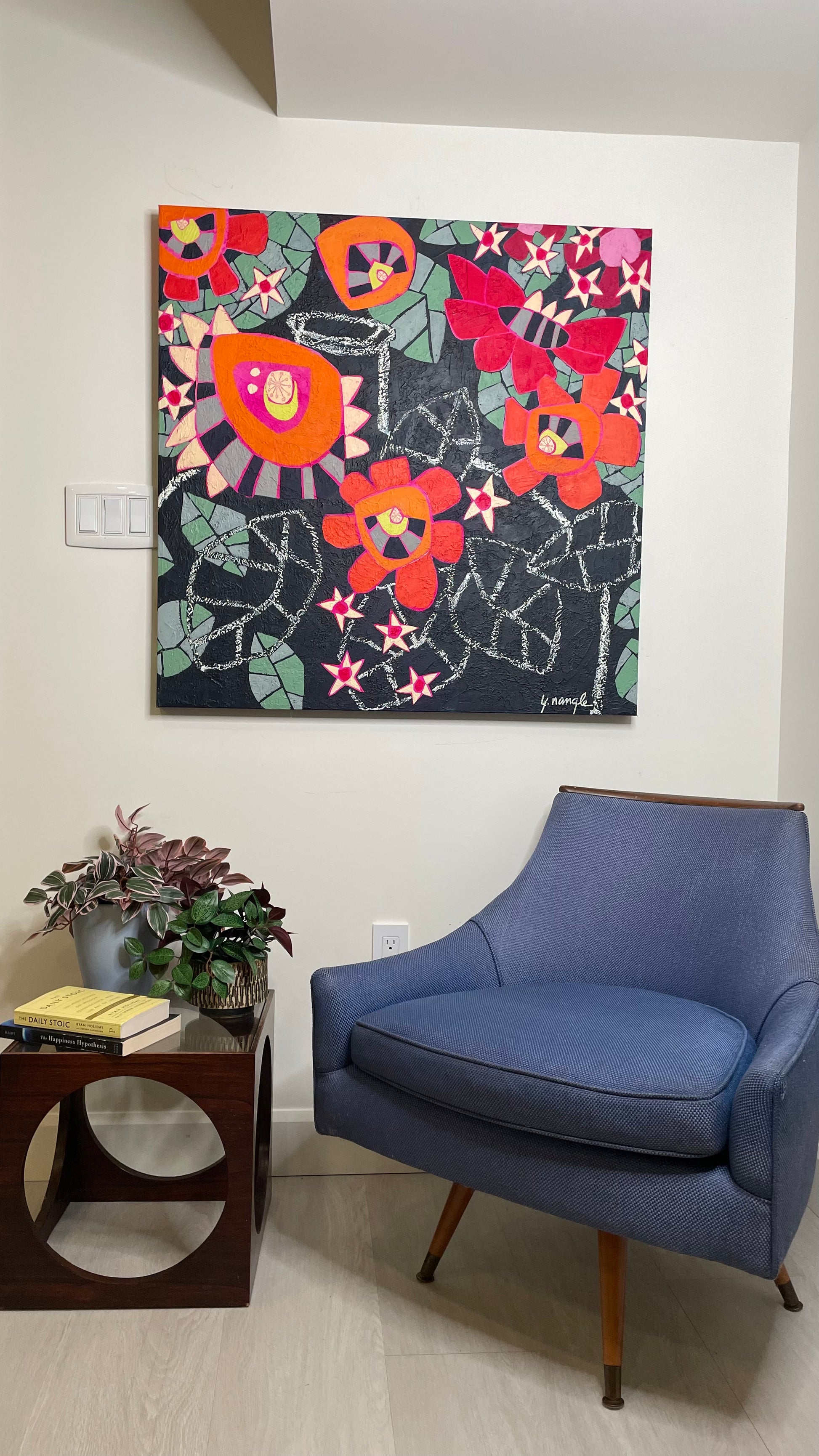 large colourful abstract floral painting with red and orange blooms displayed in a neutral interior creating a bold focal point